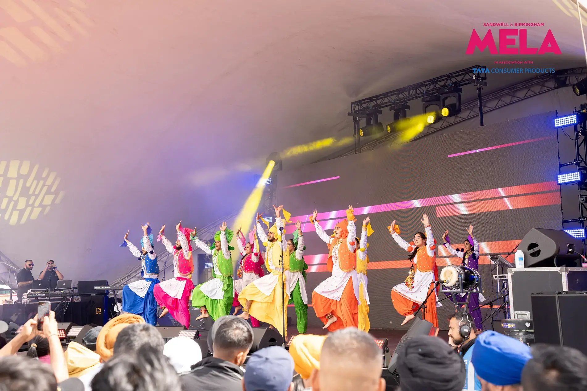 Jodi Dancers performing bhangra on the main stage at the Sandwell and Birmingham Mela in front of a large crowd