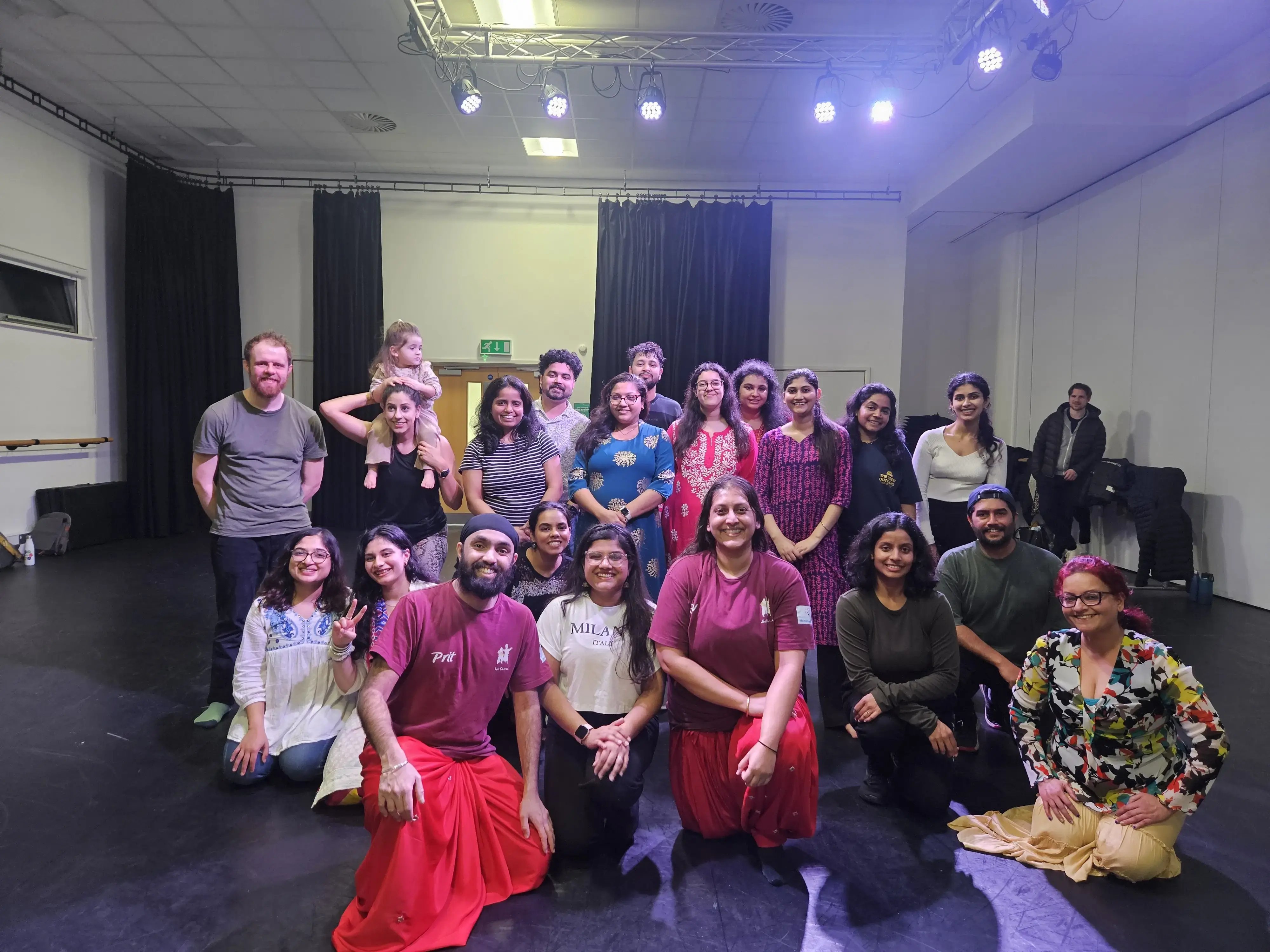 Group of adults and a child posing together after a community dance workshop in a studio space.